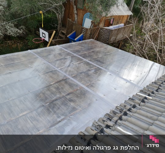 גג פלסטיק שקוף מעל מבנה עץ בגינה
